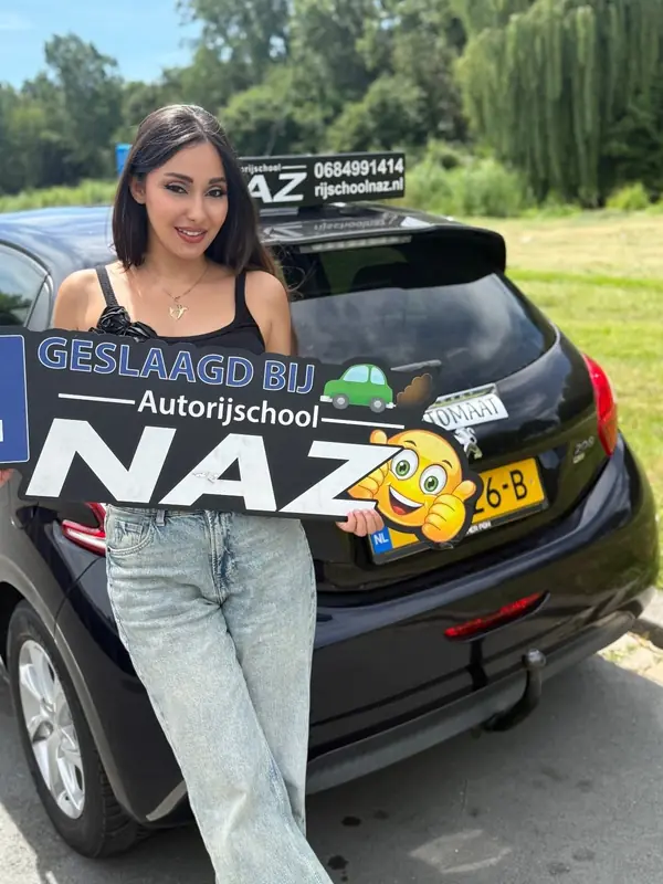 Geslaagde leerling met het bord Geslaagd bij Autorijschool NAZ voor de automaat-lesauto