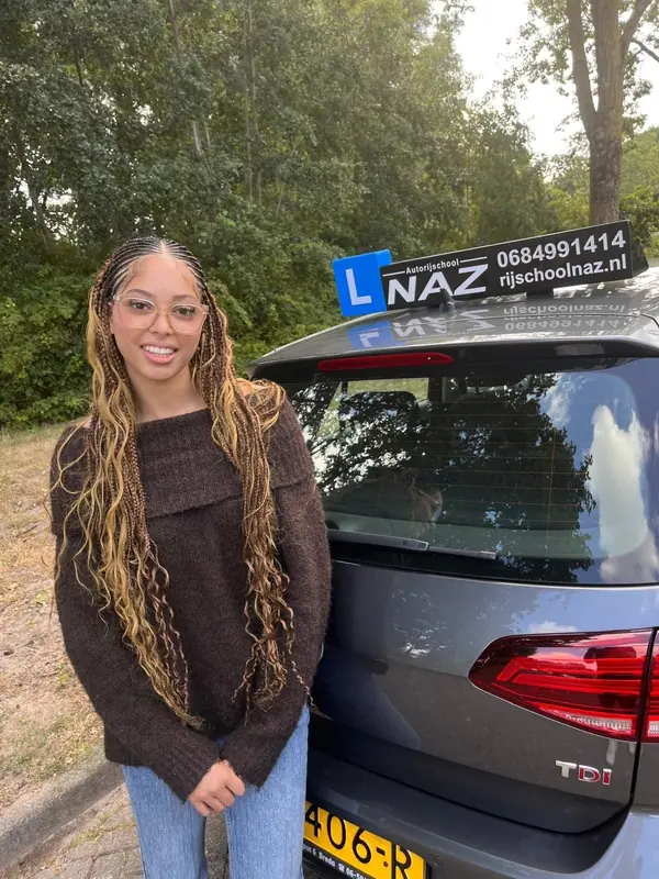 Geslaagde leerling naast de lesauto van NAZ