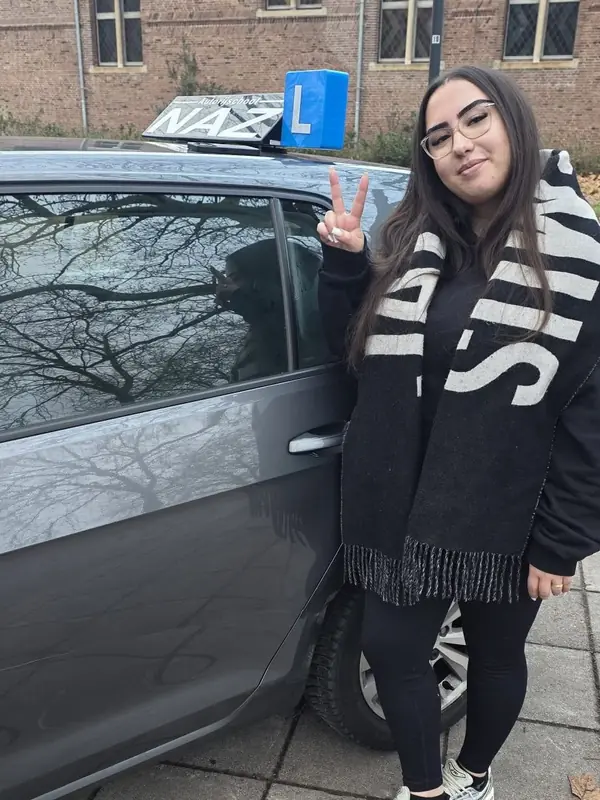 Geslaagde leerling bij de lesauto van NAZ