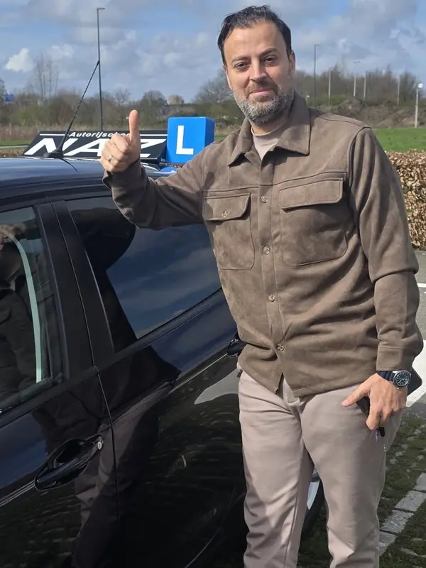 Geslaagde leerling bij de lesauto van NAZ