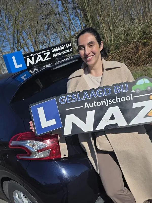 Geslaagde leerling met het bord Geslaagd bij Autorijschool NAZ